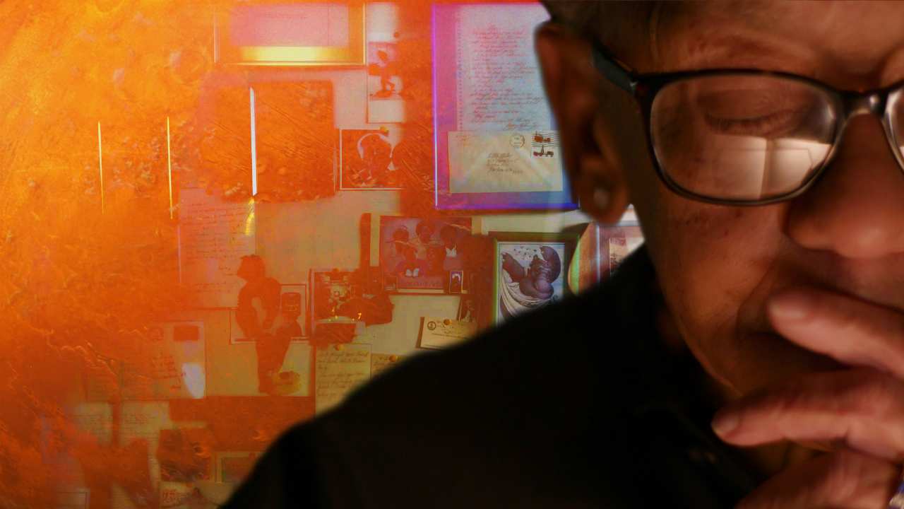 a woman with glasses in front of an orange wall
