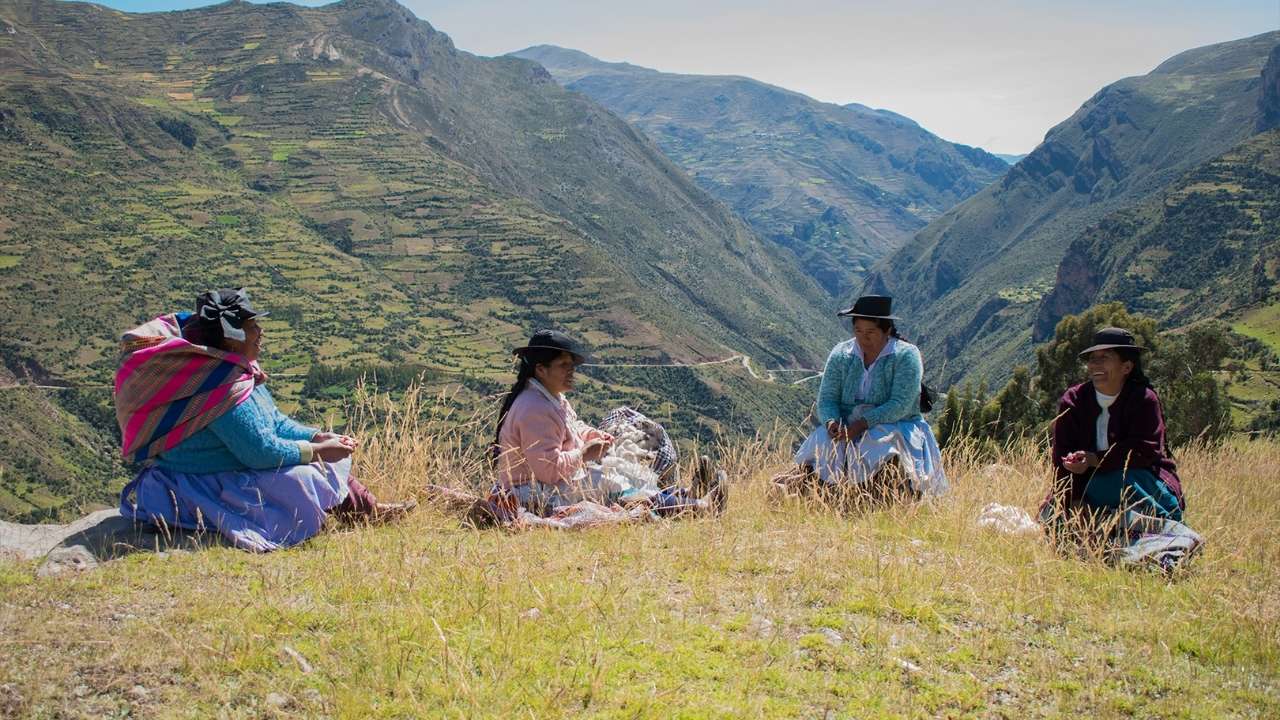 four women sitting on a grassy hill