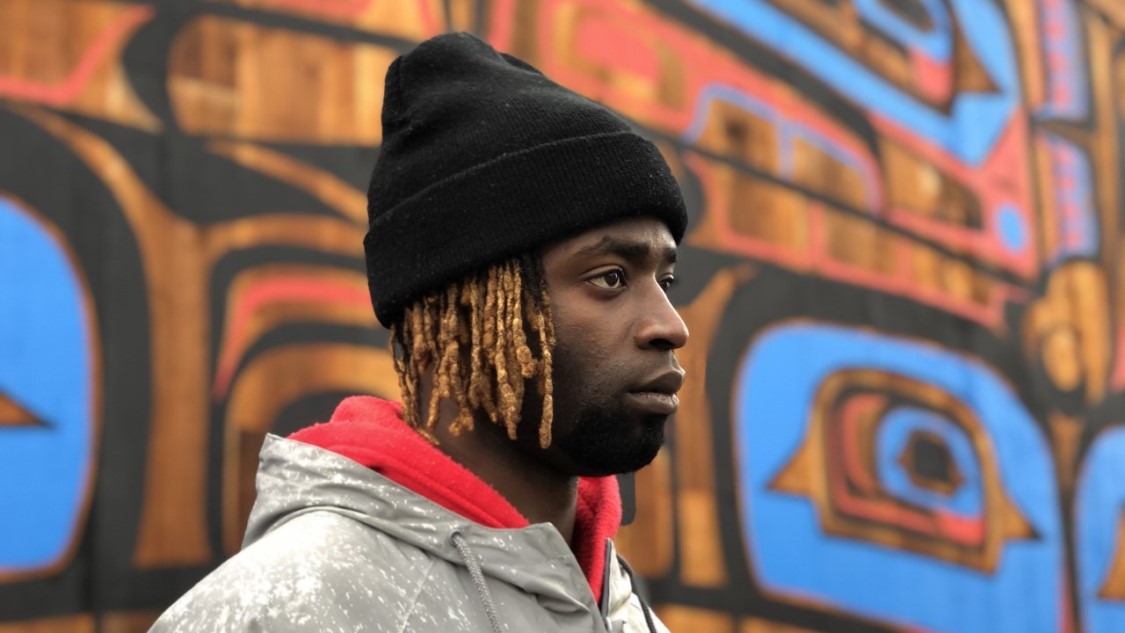 Black man in front of Indigenous art