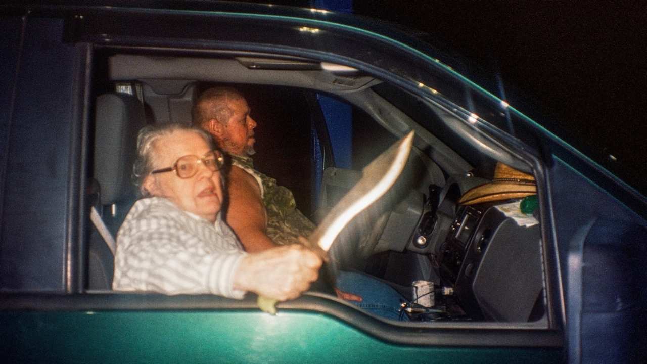 a woman with a knife sitting next to a man in a car