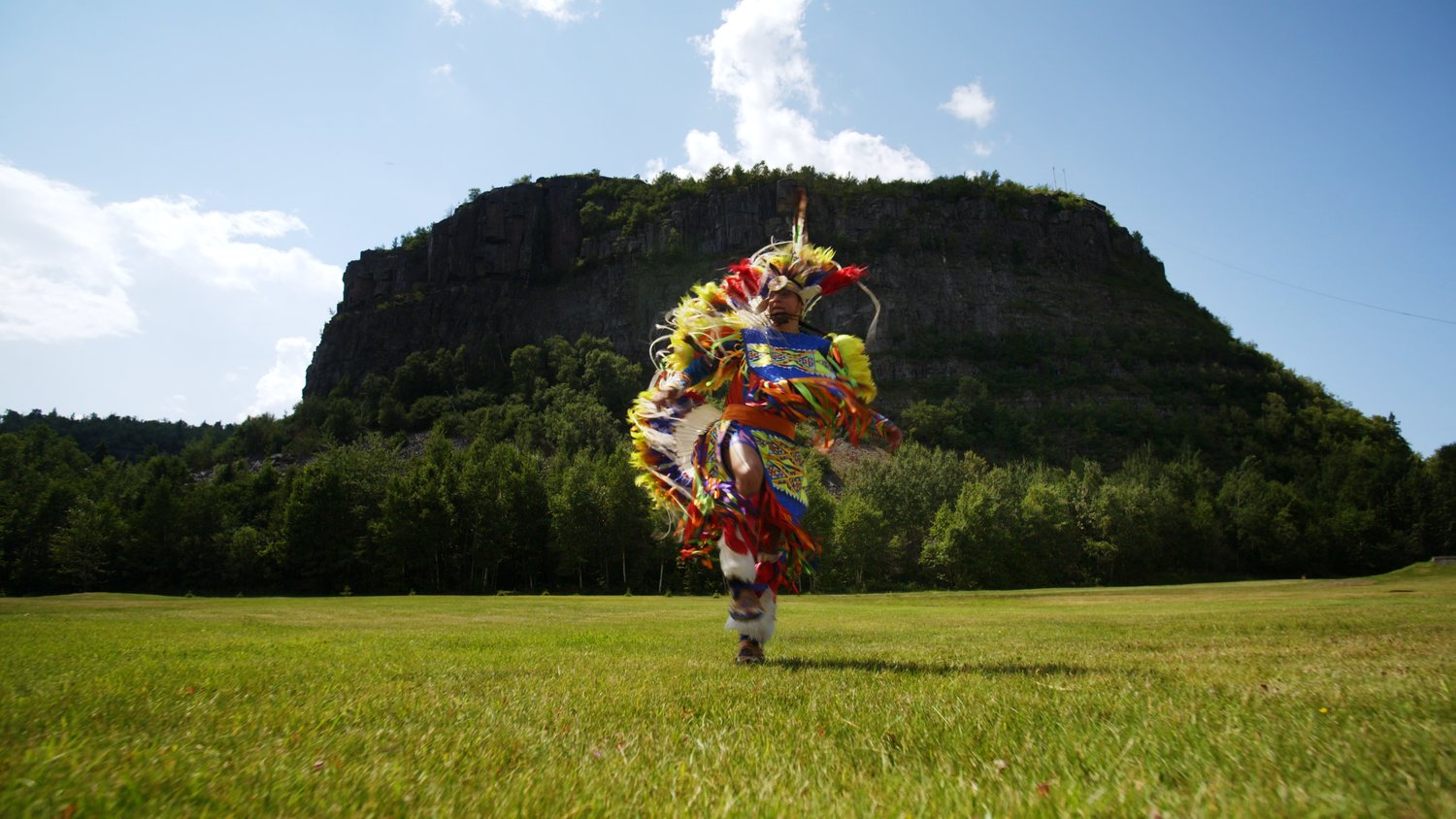 Indigenous person in bright pow wow clothing